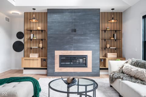 Living room at 16246 Remington Drive, Fishers, IN — Modern fireplace with custom wood slat accent wall design.