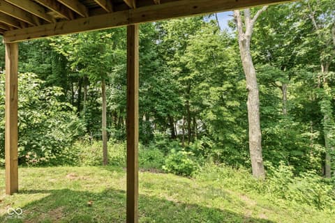 Outdoor living area at 14442 Treasure Creek Lane, Fishers, IN — Covered deck with serene wooded backdrop and mature trees.