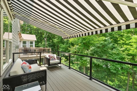 Outdoor living area at 14442 Treasure Creek Lane, Fishers, IN — Modern deck with retractable awning and wooded views.