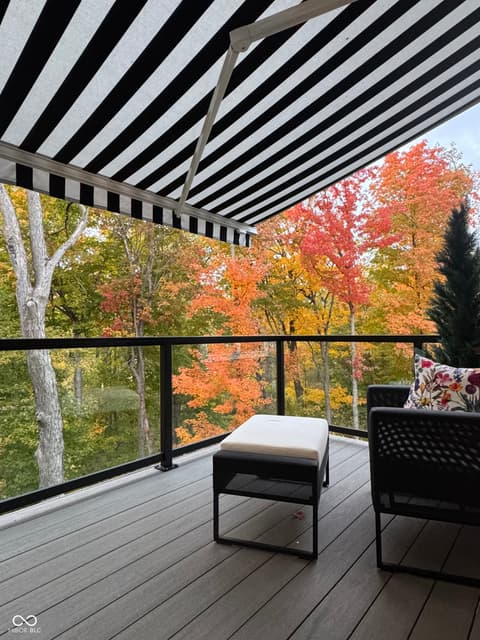 Outdoor living area at 14442 Treasure Creek Lane, Fishers, IN — Modern deck with retractable awning and scenic views.
