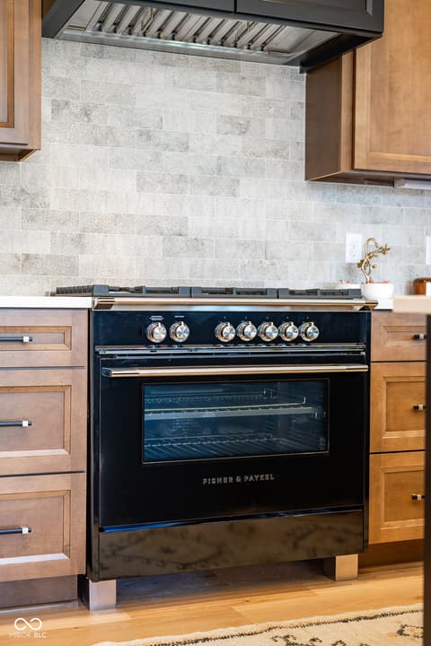 Kitchen at 14565 Bedford Falls Drive, Carmel, IN — Chef's kitchen with luxury gas range and marble backsplash.