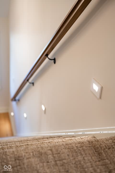 Hallway at 14565 Bedford Falls Drive, Carmel, IN — Modern hallway with recessed lighting and sleek handrail.