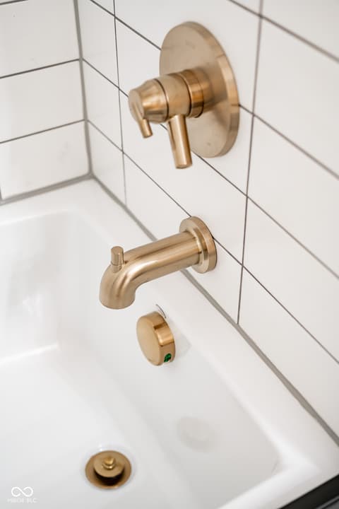 Primary bathroom at 14565 Bedford Falls Drive, Carmel, IN — Spa-like bath with modern brass fixtures and subway tile.