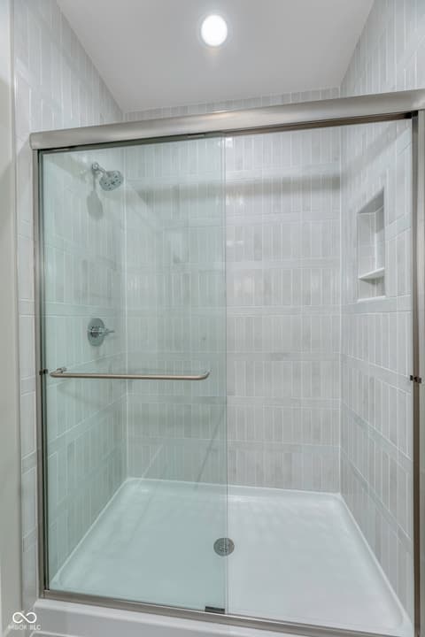 Primary bathroom at 8694 Morgan Drive, Fishers, IN — Sleek modern shower with vertical tile and glass enclosure.