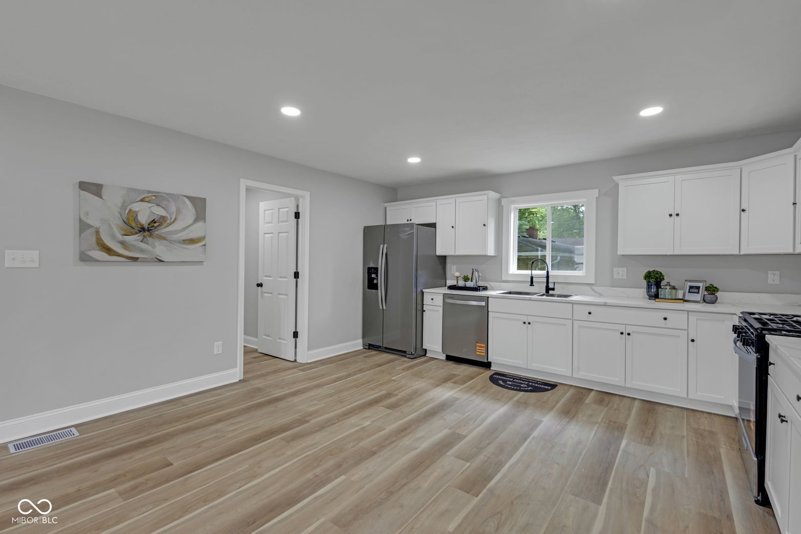 Bright modern kitchen with white cabinets and hardwood floors.
