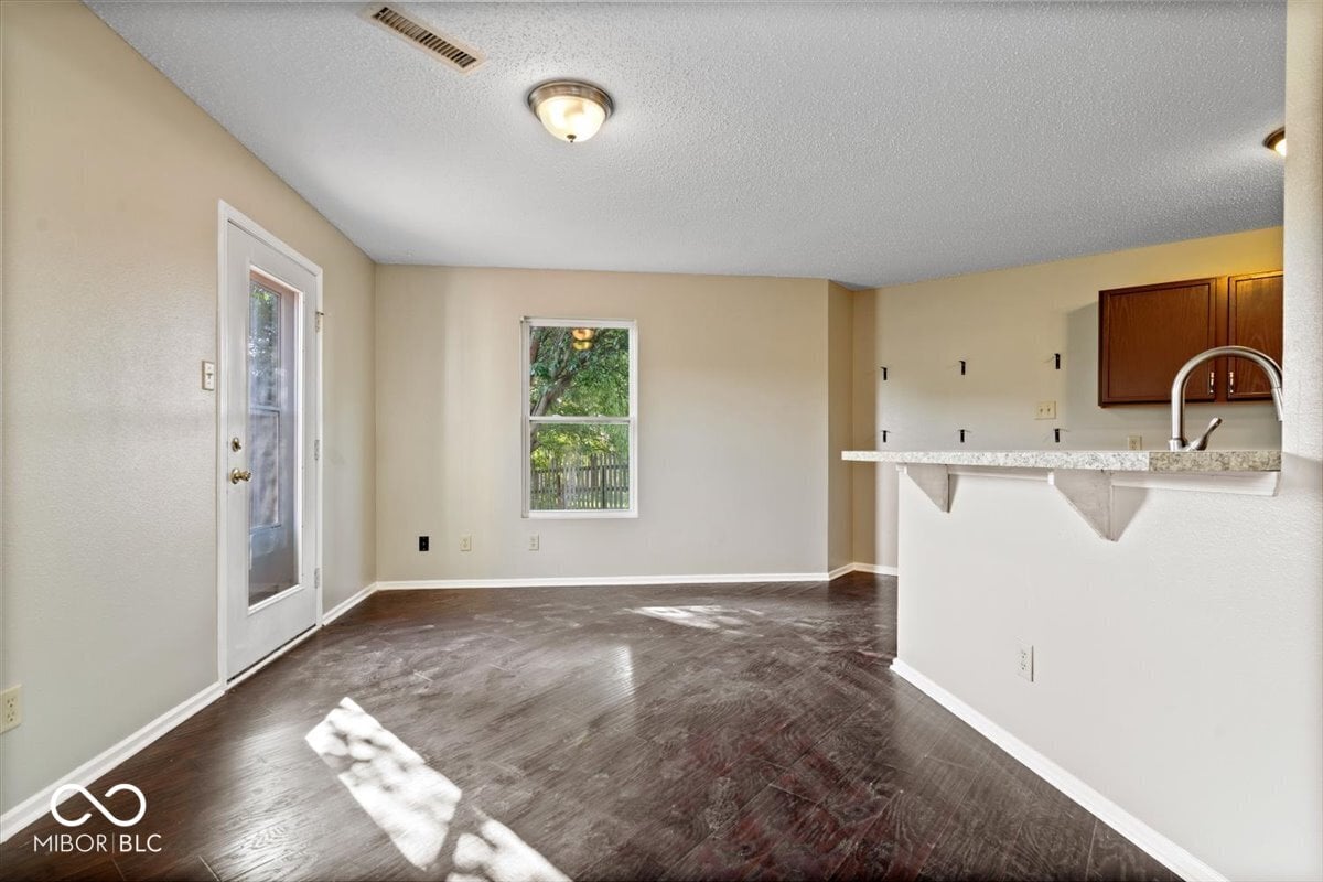 Bright kitchen with dark hardwood floors and granite counters.