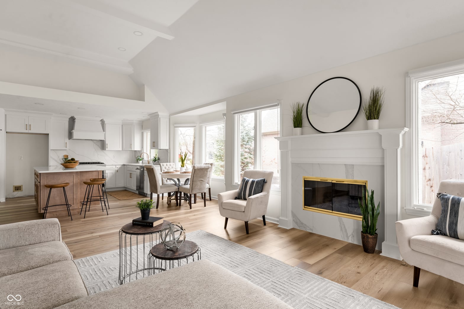 Bright open-concept living space with fireplace and abundant windows.