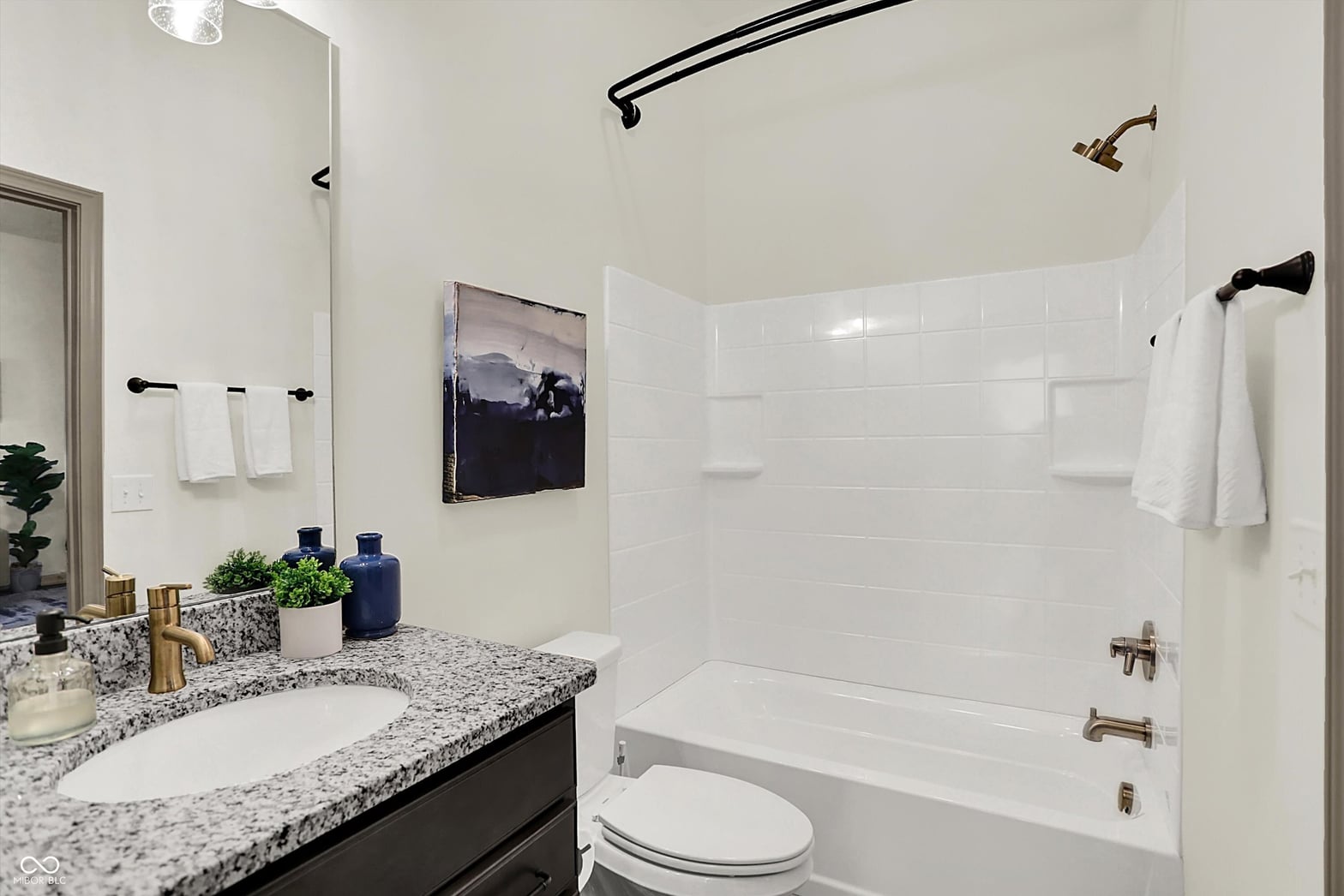Luxurious primary bathroom with granite counters and subway tile.