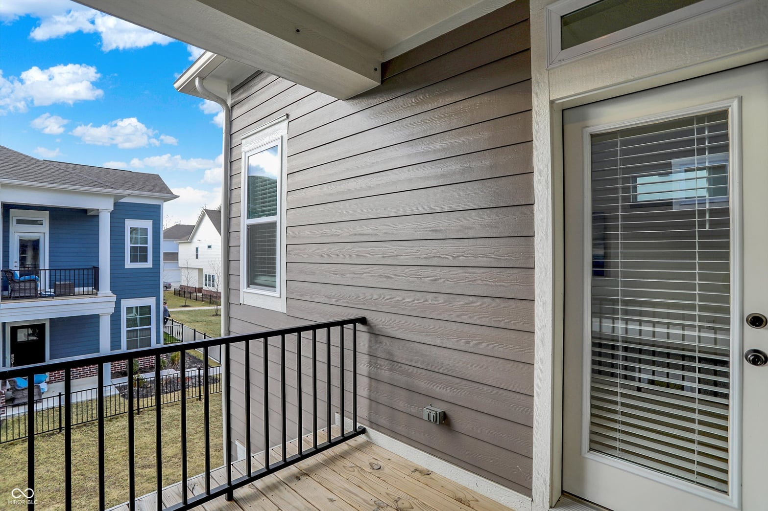 Modern deck with black railings overlooking established neighborhood.