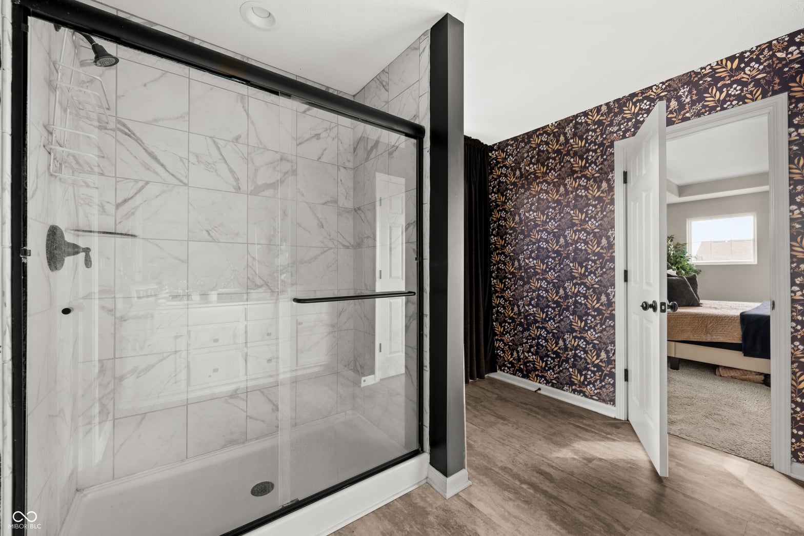 Luxurious primary bath with frameless glass shower and marble tile.
