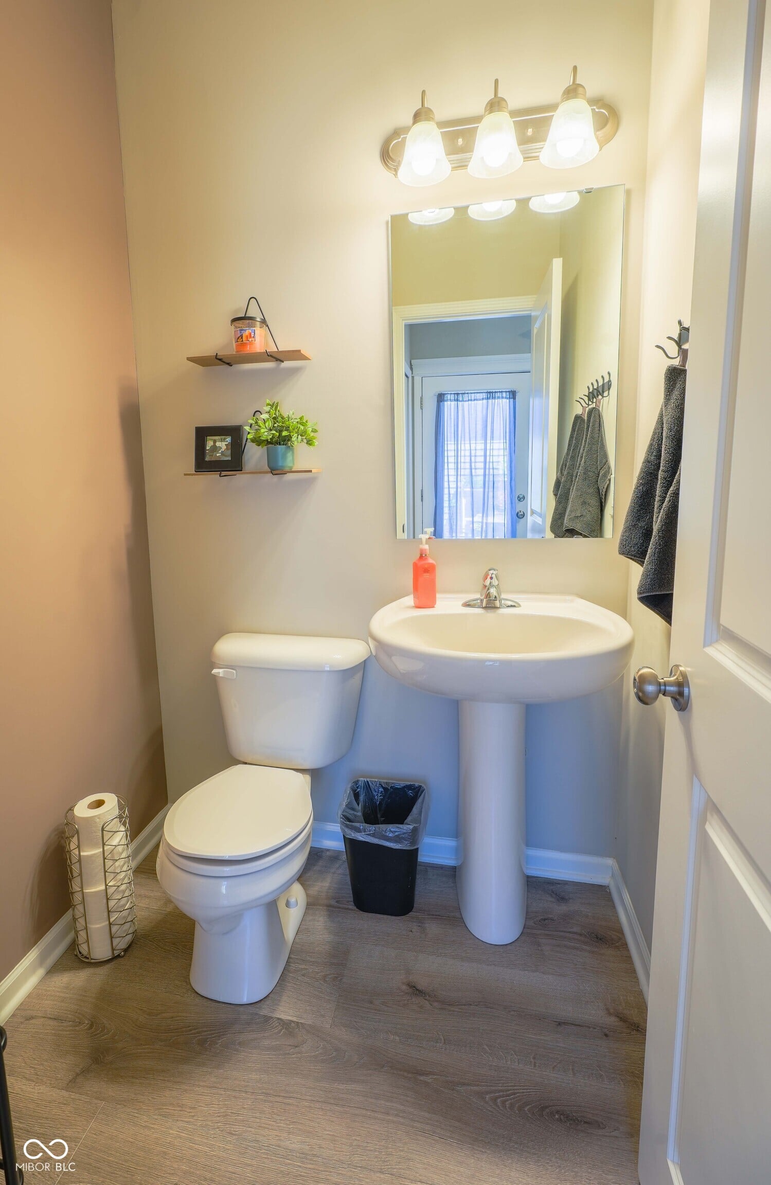 Bright, organized bathroom with modern pedestal sink setup.