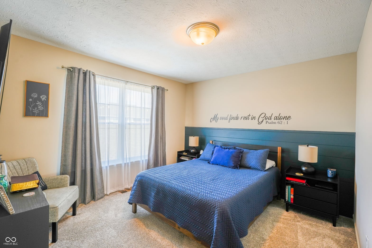 Bright primary bedroom with blue accent headboard and natural light.