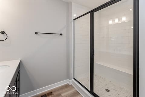 Primary bathroom at 408 Elite Street, Westfield, IN — Luxurious modern walk-in shower with black frame enclosure.