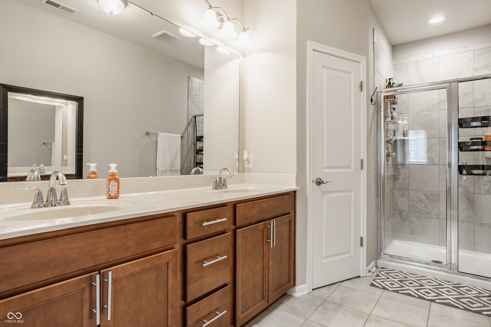Elegant primary bath with dual vanity and frameless glass shower.