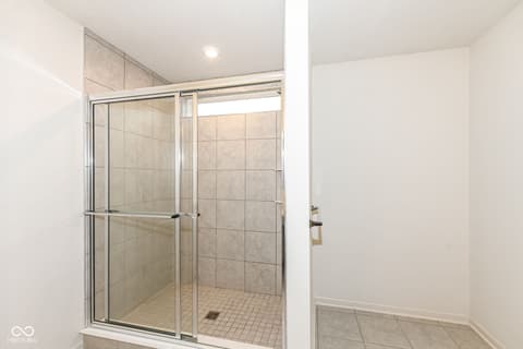 Primary bathroom at 15104 Downham Drive, Fishers, IN — Modern frameless glass shower with neutral tile design.