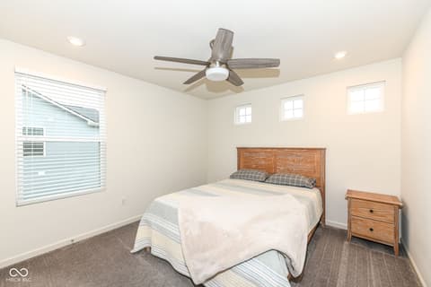 Bedroom at 15104 Downham Drive, Fishers, IN — Bright bedroom with multiple windows and modern ceiling fan.