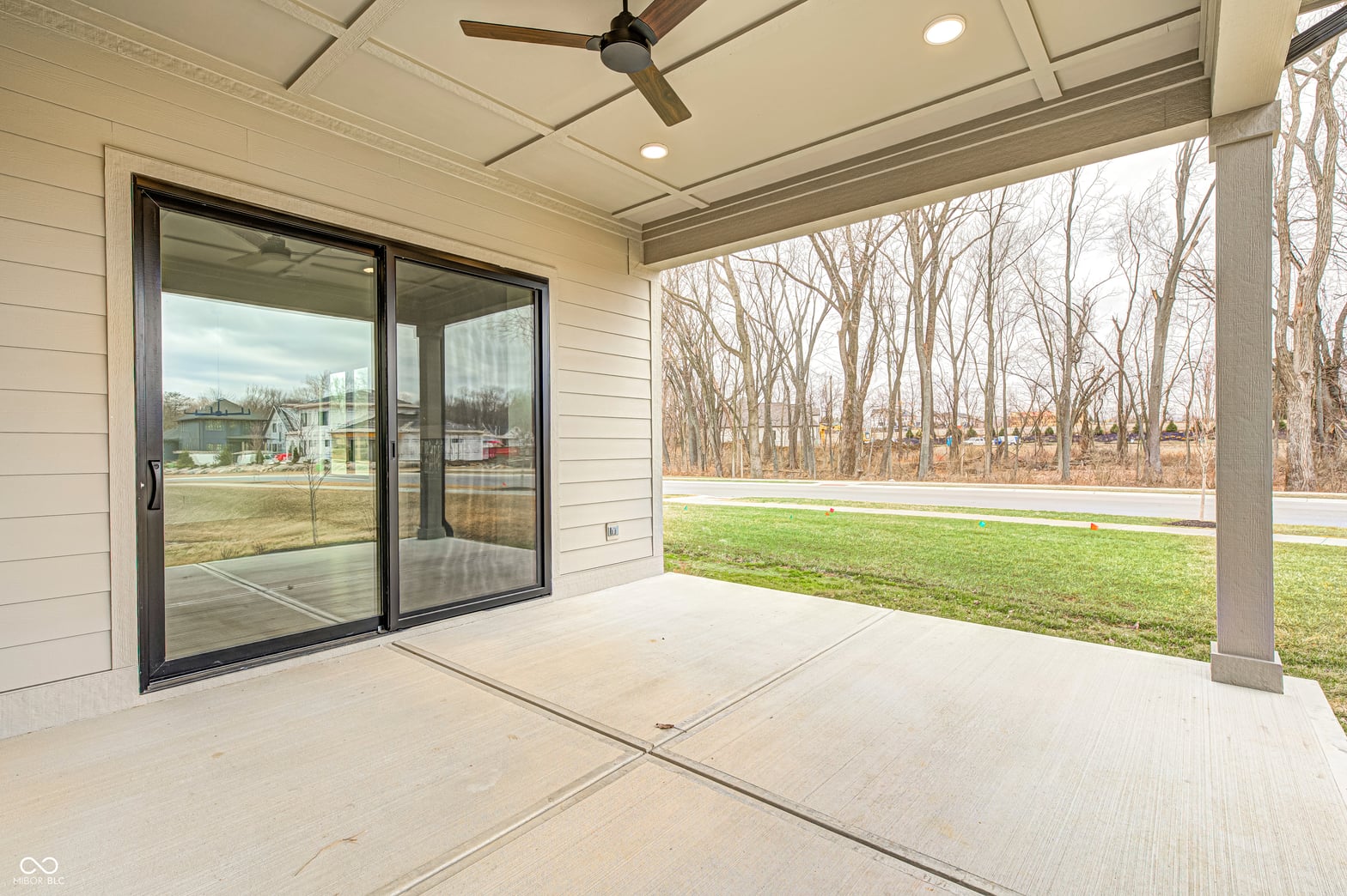 Spacious covered patio with modern glass doors and yard views.
