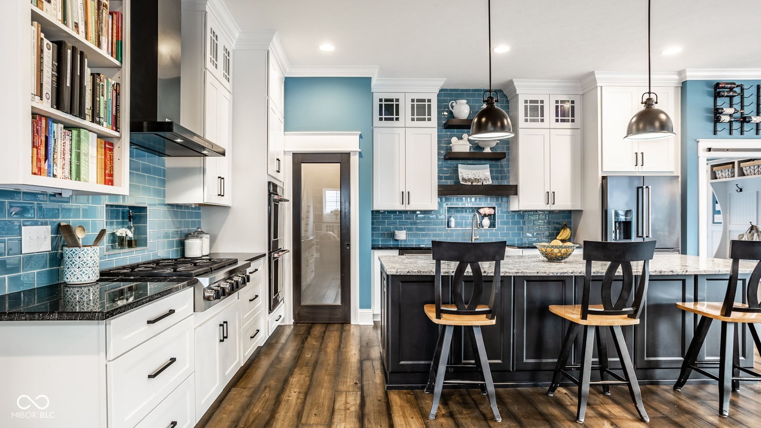 Modern kitchen with blue tile, white cabinets, and island seating.
