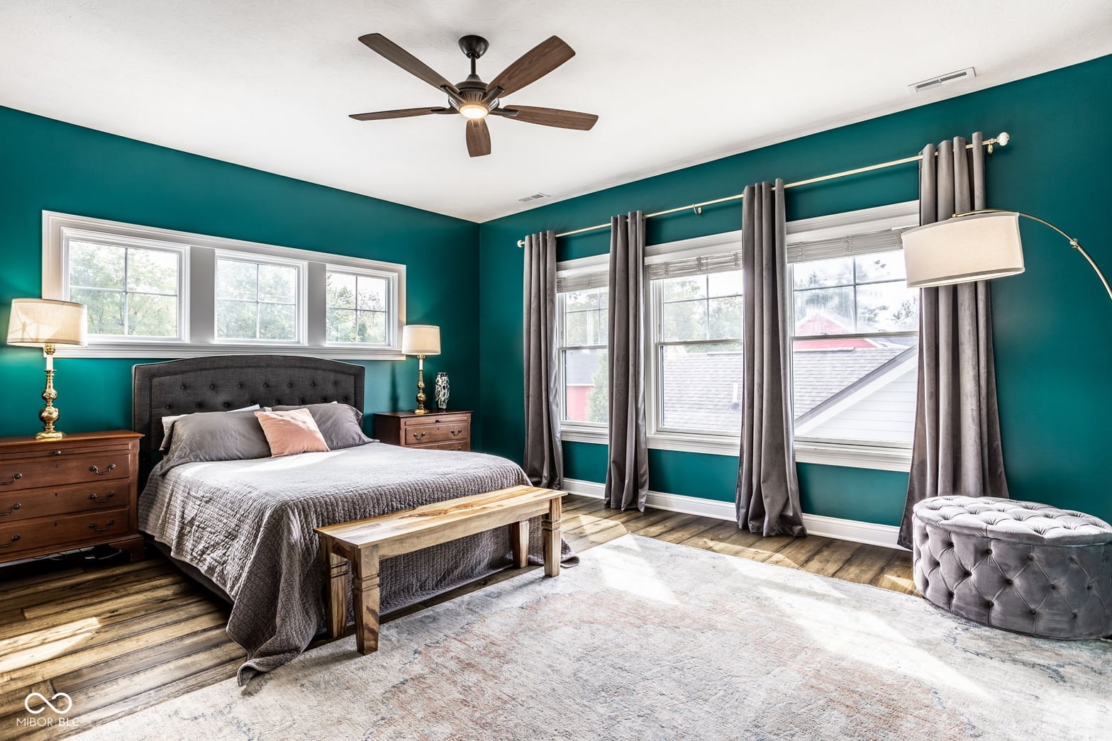Spacious primary bedroom with bold teal walls and abundant natural light.