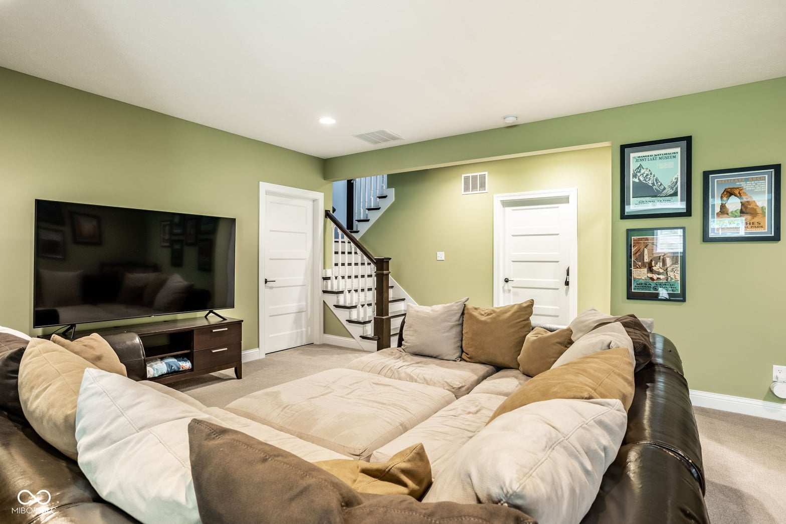 Spacious finished basement with entertainment setup and staircase access.