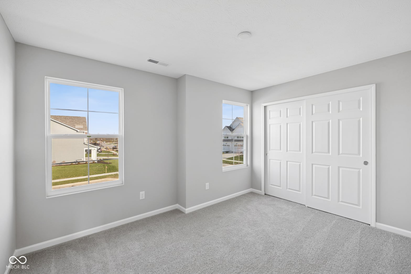 Bright primary bedroom with oversized windows and walk-in closet.