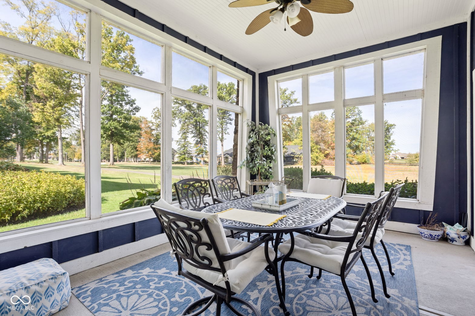 Bright sunroom with expansive windows overlooking manicured grounds.