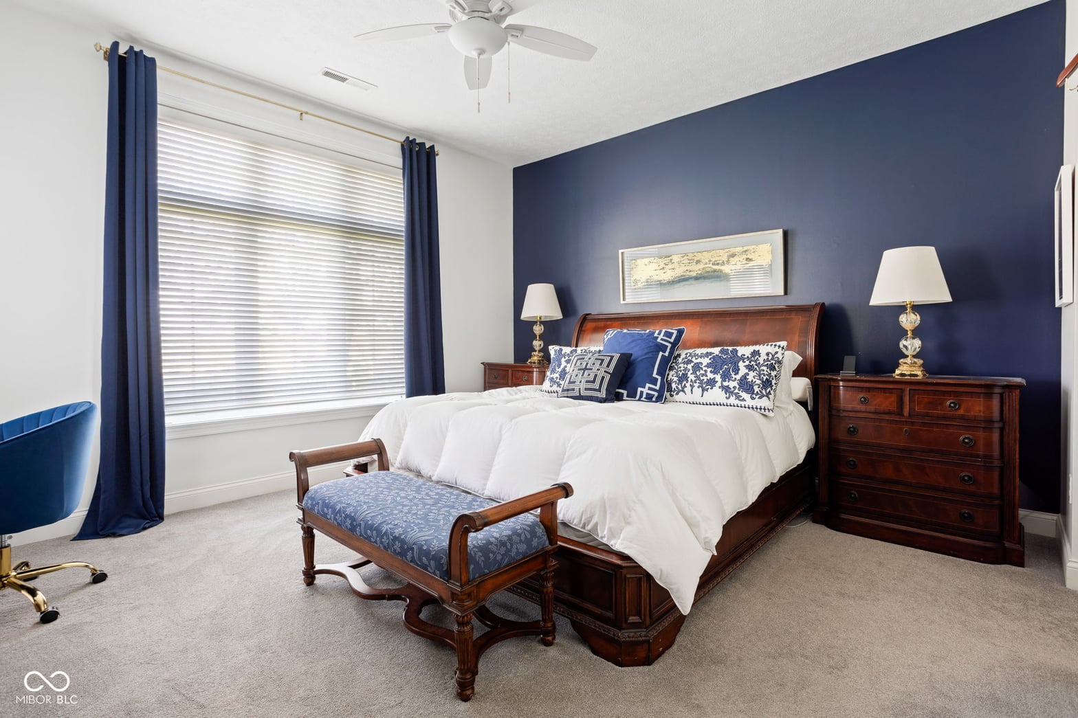 Spacious primary bedroom with elegant navy accent wall.