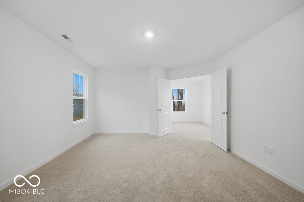 Spacious primary bedroom with abundant natural light and dual closets.