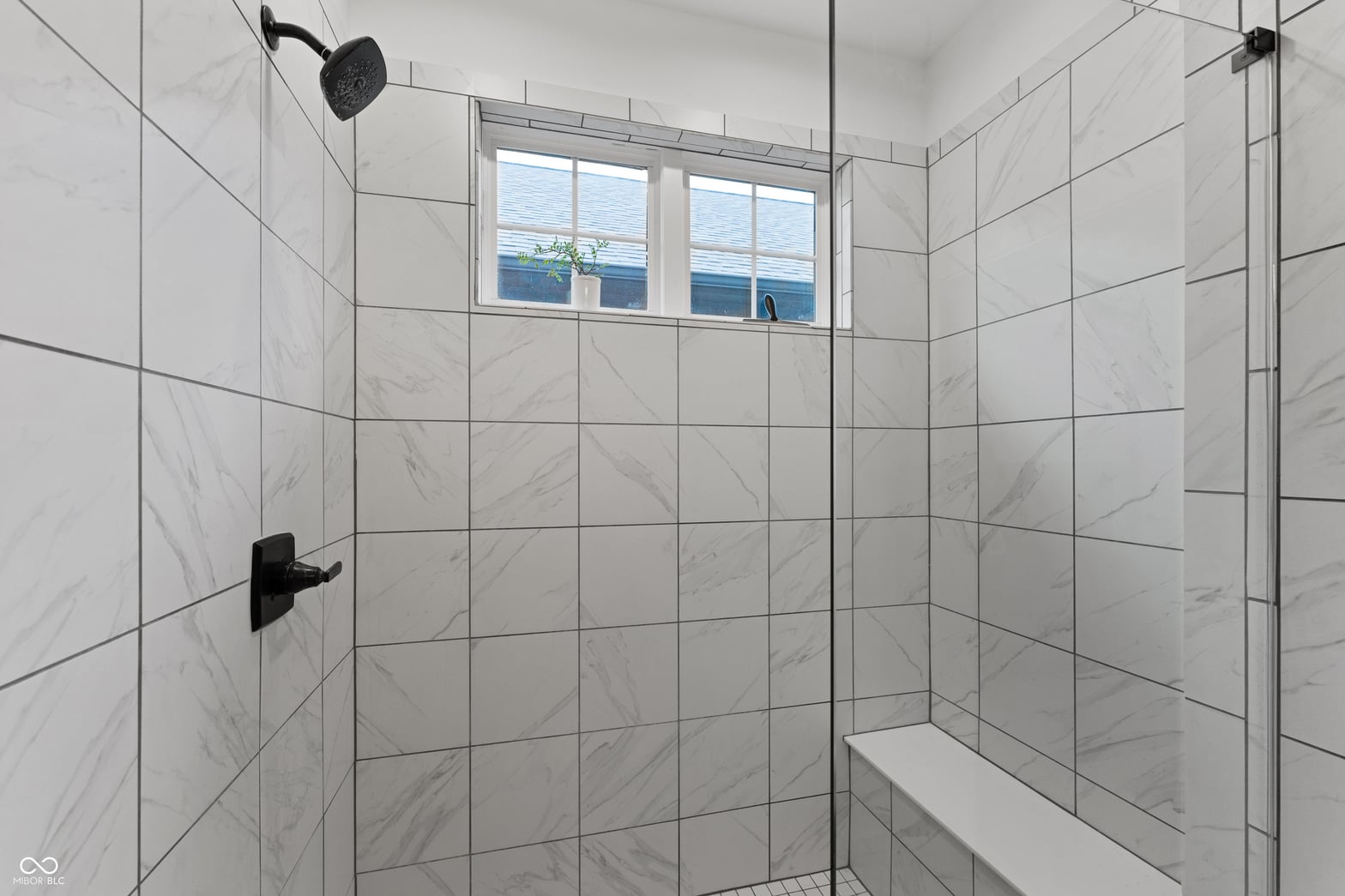 Luxurious marble shower with frameless glass enclosure.