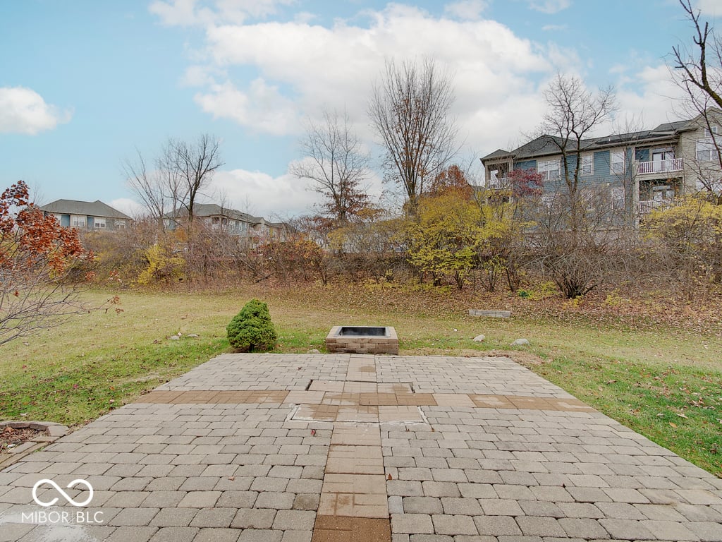 Spacious backyard with paver patio and mature trees.