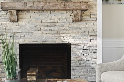 Living room at 4301 Stone Lake Drive, Zionsville, IN — Modern stacked stone fireplace with rustic wooden mantel.