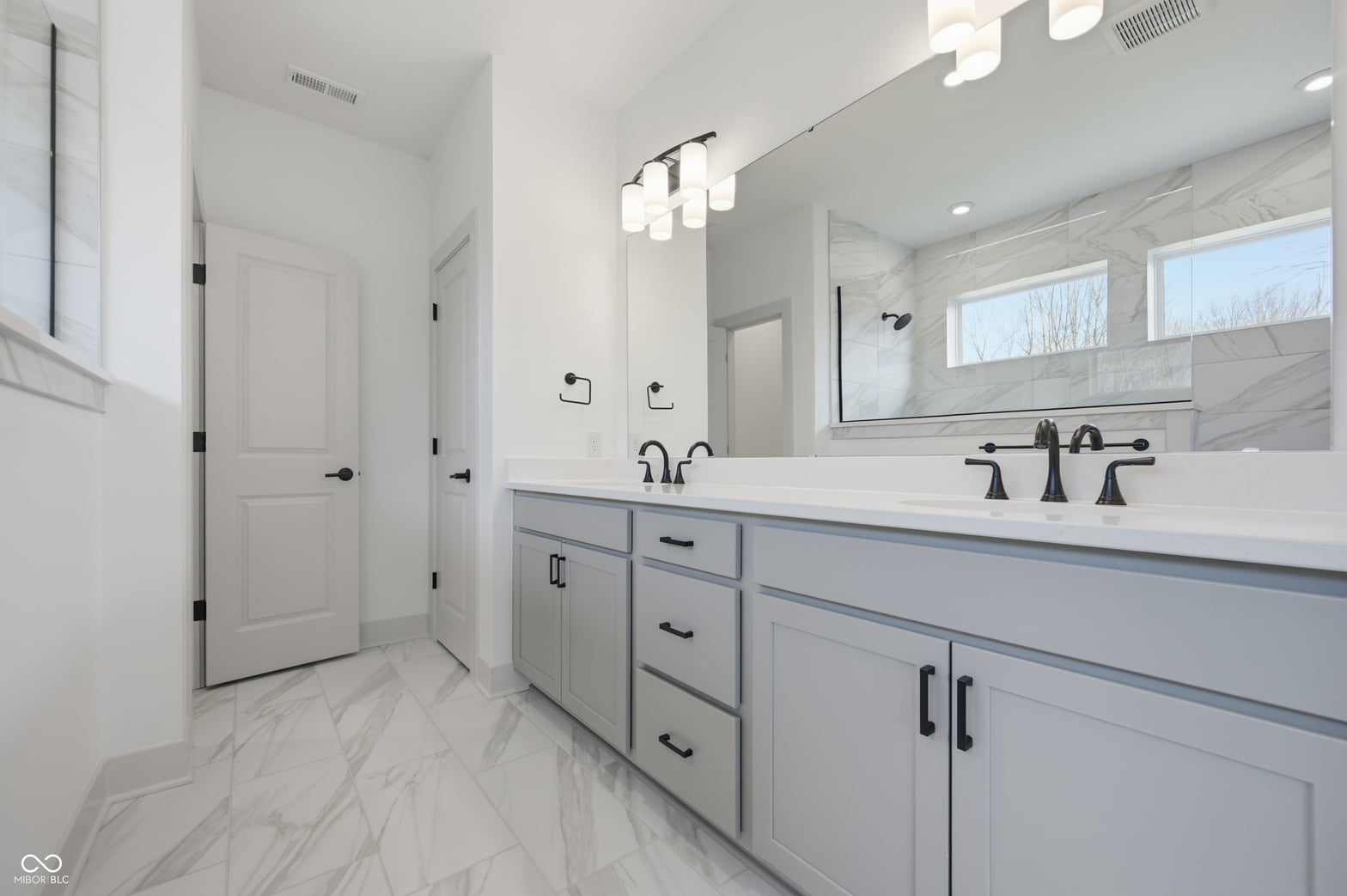 Luxurious primary bath with dual vanity and marble finishes.
