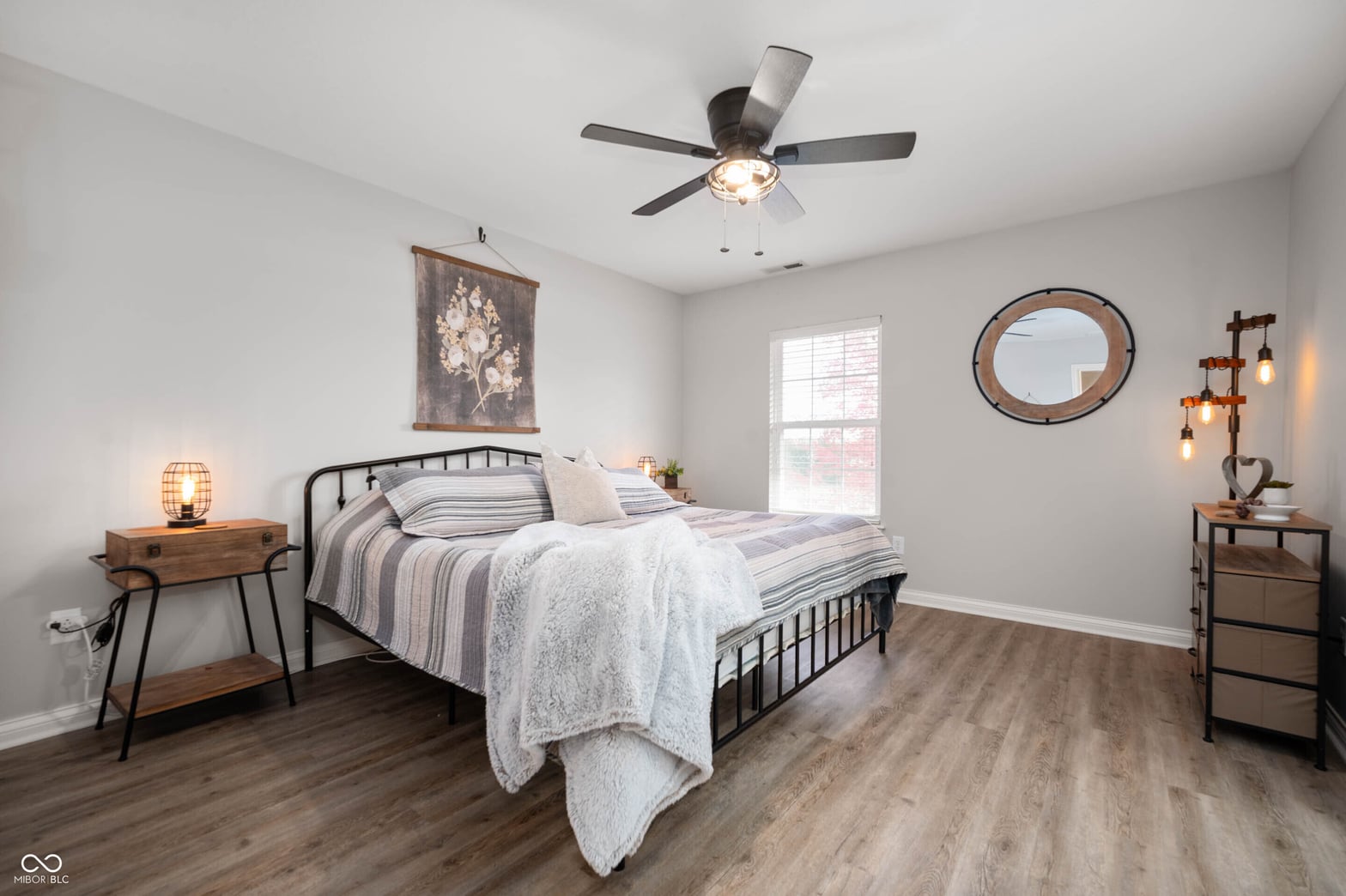 Bright, modern primary bedroom with hardwood floors and updated fixtures.