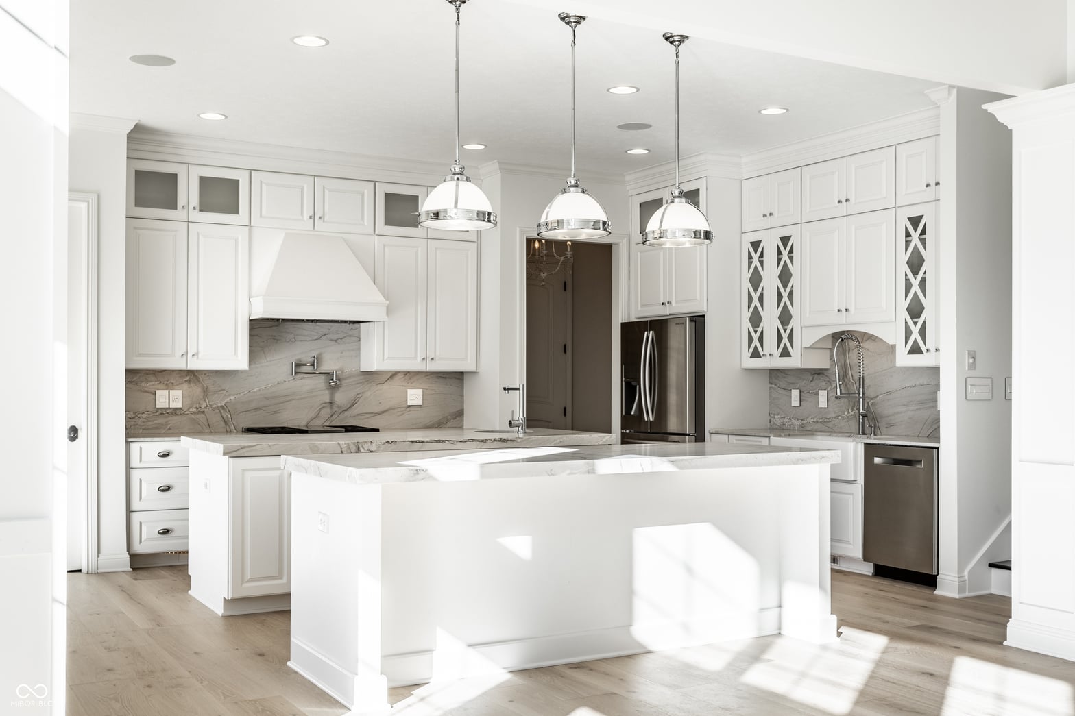 Stunning white kitchen with marble counters and oversized island.