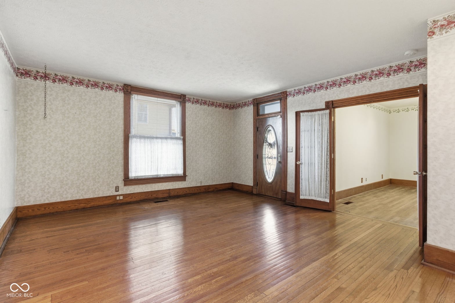 Spacious living room with original hardwood floors and wood trim.