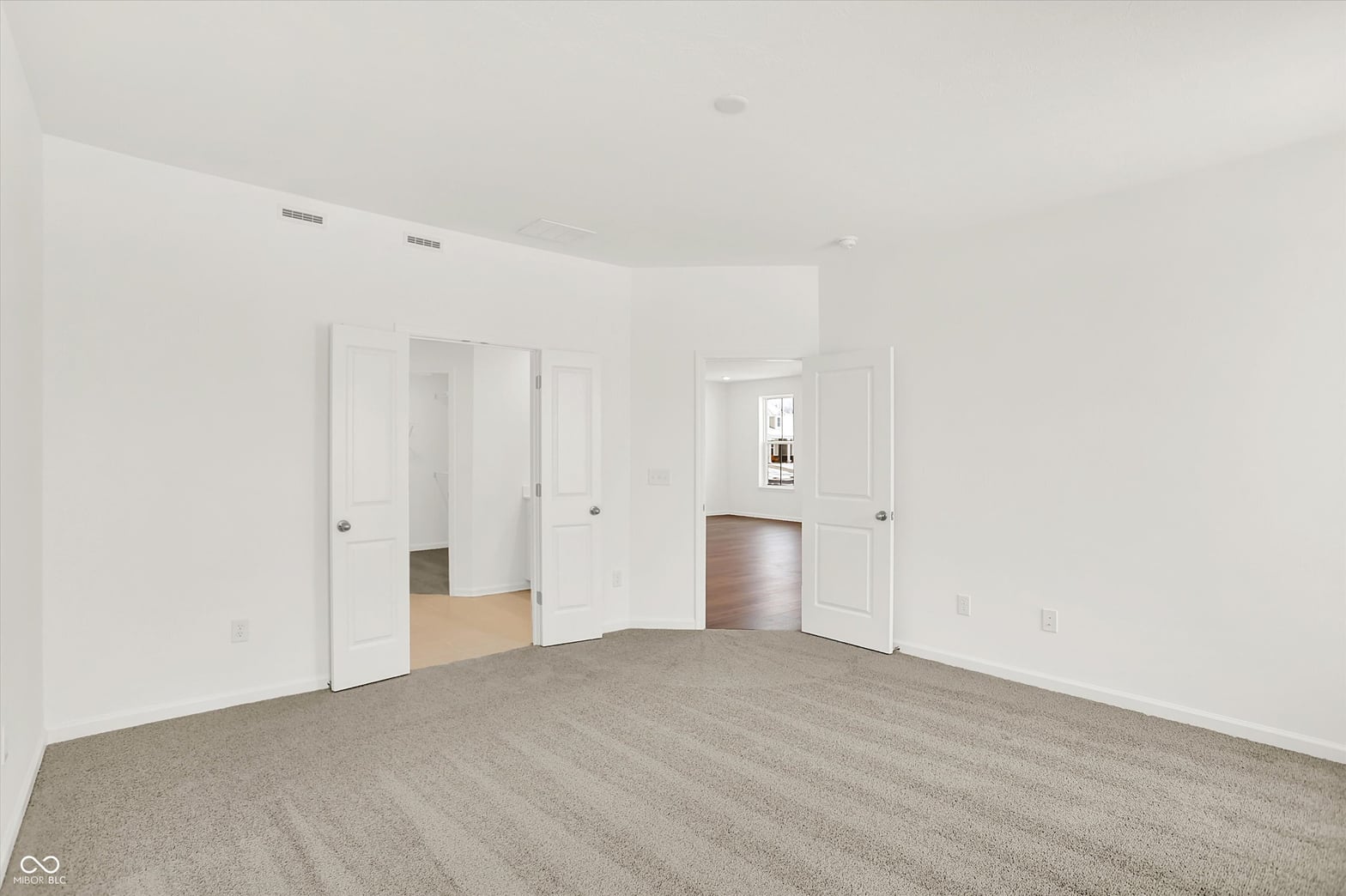 Spacious primary bedroom with multiple closets and recessed lighting.