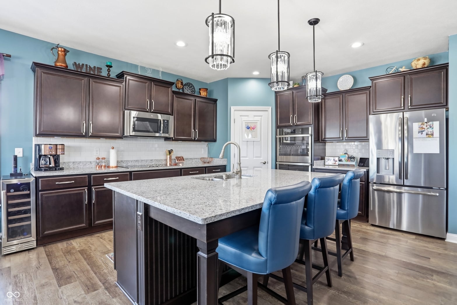 Modern kitchen with granite island and stainless steel appliances.