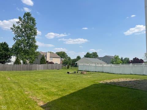 Yard at 1225 Maple Trace Way, Sheridan, IN — Large fenced yard with fire pit and mature trees.