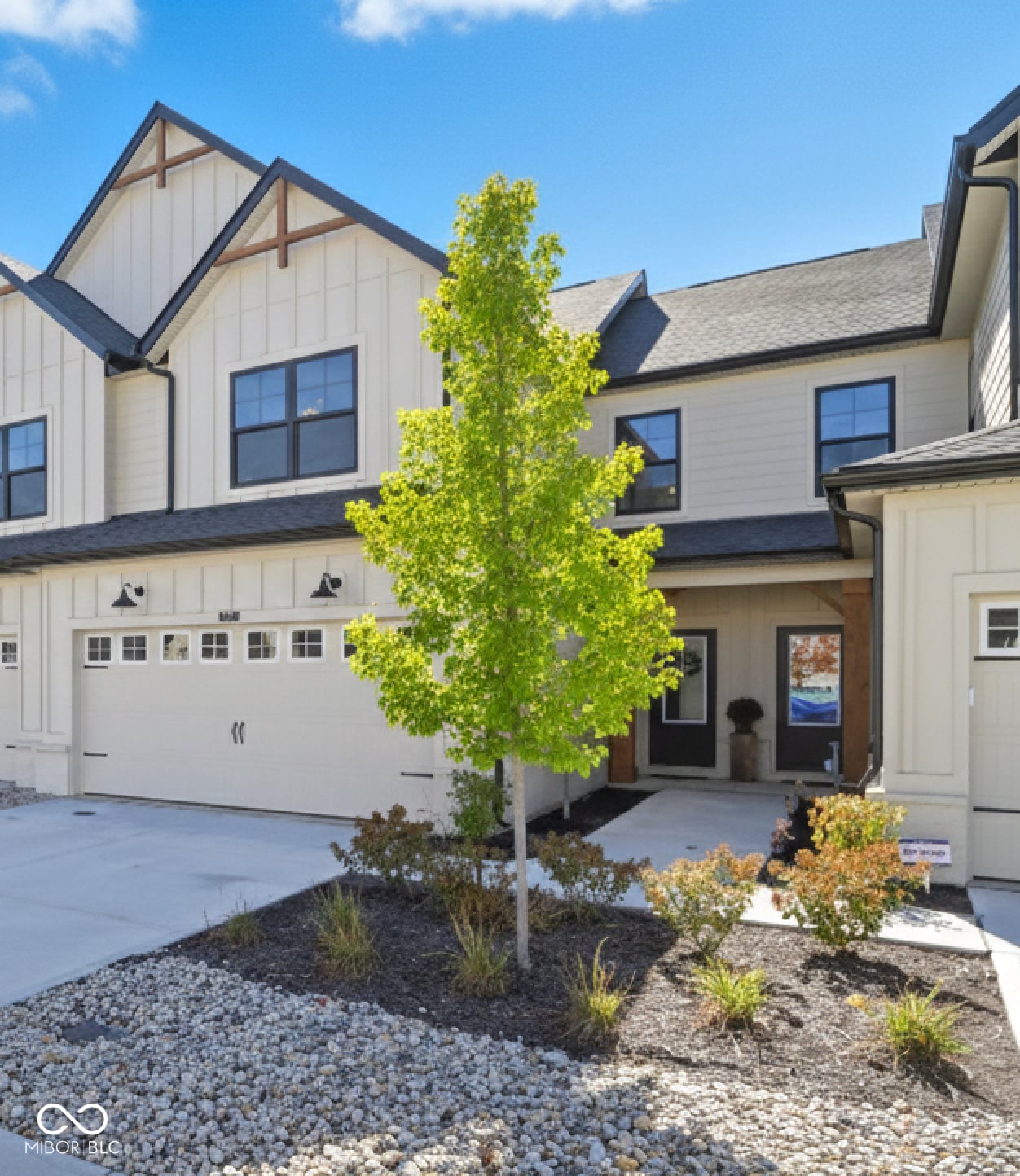 Modern farmhouse with two-car garage and landscaped grounds.