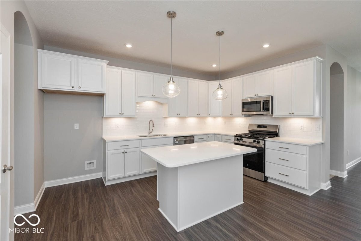 Modern kitchen with white cabinets and quartz island.