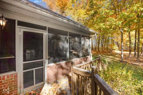 Outdoor living area at 10791 E State Road 47, Sheridan, IN — Screened porch overlooks serene wooded landscape.