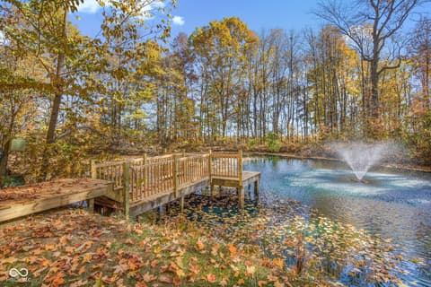 Outdoor living area at 10791 E State Road 47, Sheridan, IN — Serene pond-side deck in wooded setting.
