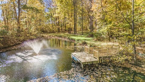 Yard at 10791 E State Road 47, Sheridan, IN — Serene wooded property with pond and fountain.