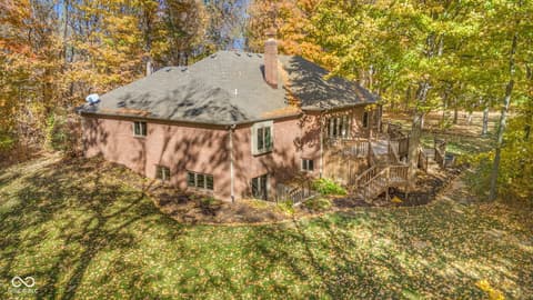 Backyard at 10791 E State Road 47, Sheridan, IN — Brick home nestled among mature trees with spacious deck.