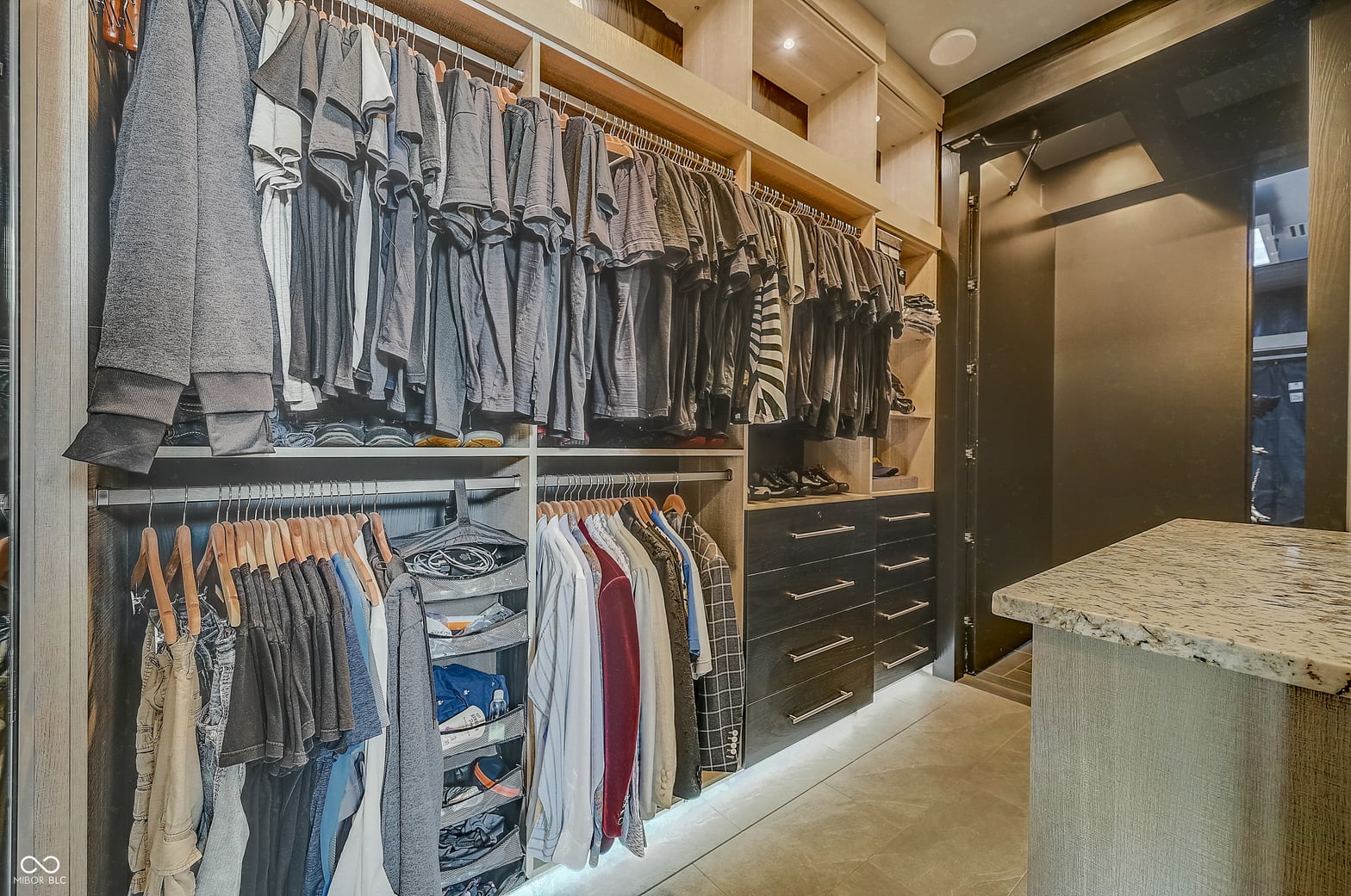 Luxurious walk-in closet with custom organization and marble island.