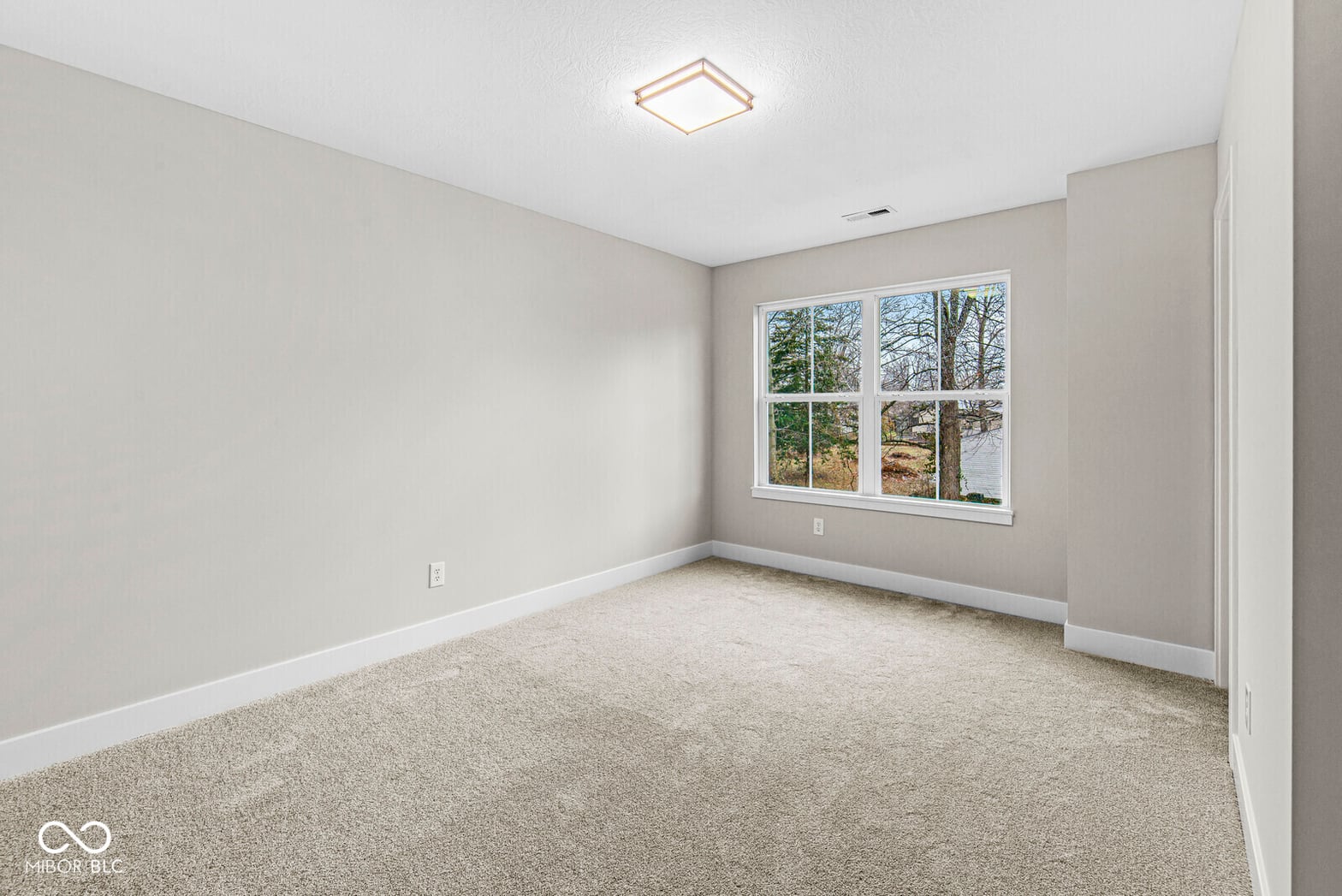Bright bedroom with large windows and neutral finishes.