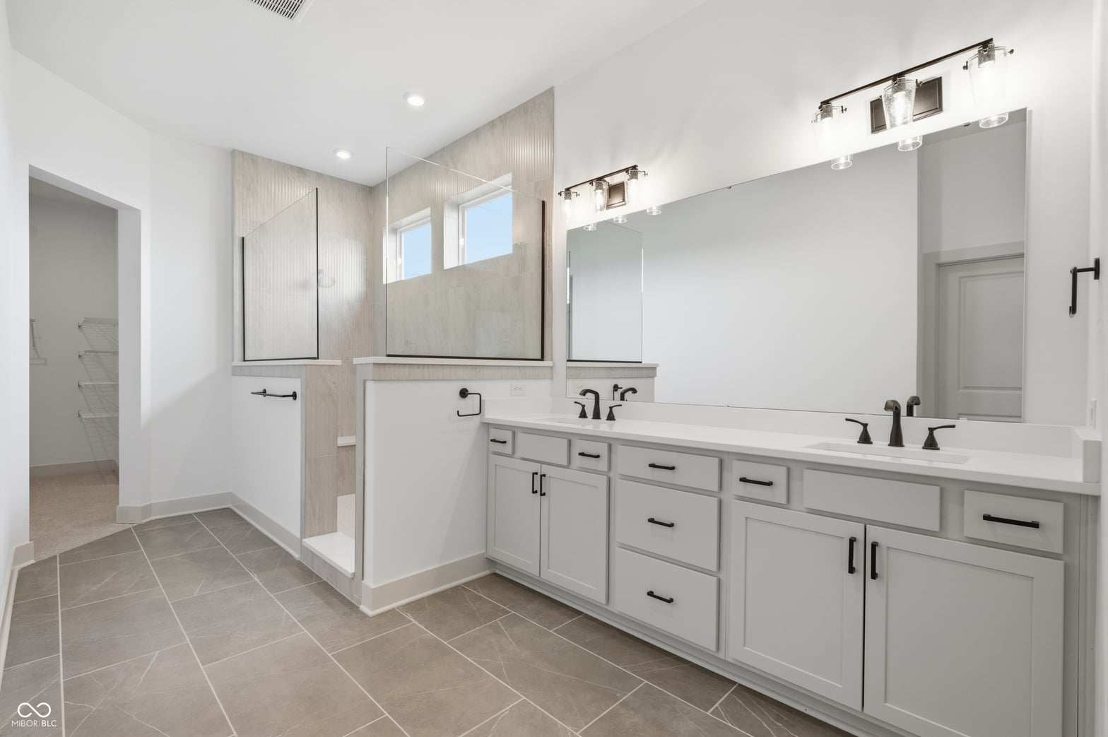 Luxurious primary bath with dual vanity and frameless shower.