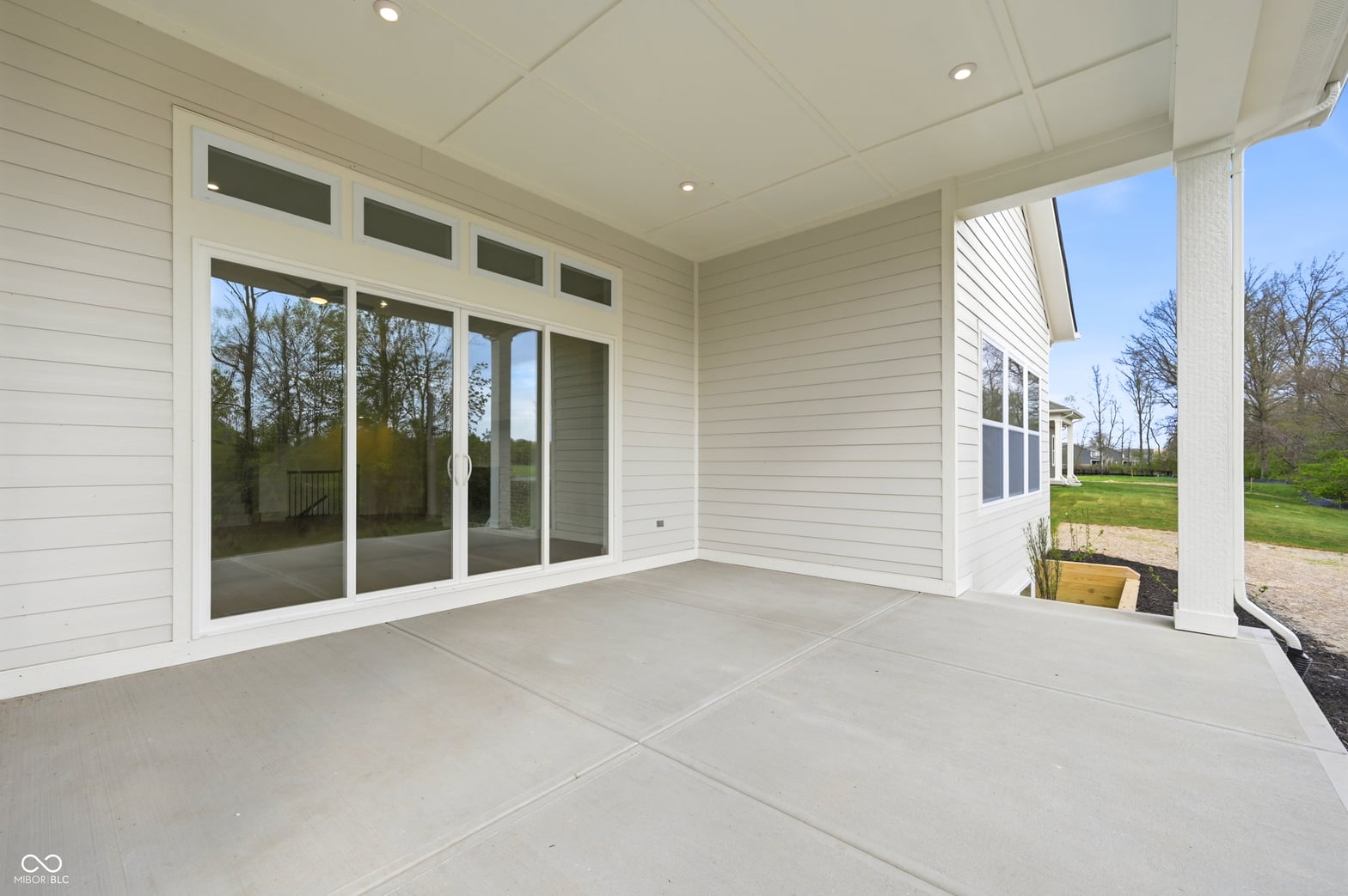 Bright covered patio with expansive glass doors and views.