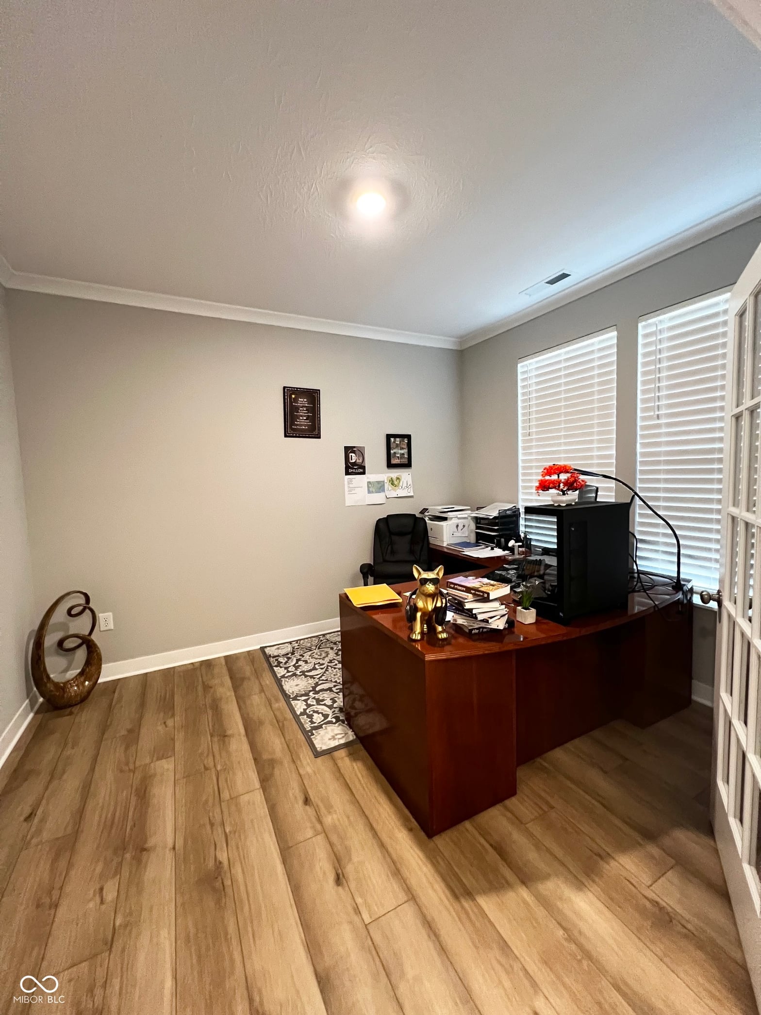 Spacious home office with hardwood floors and shutters.