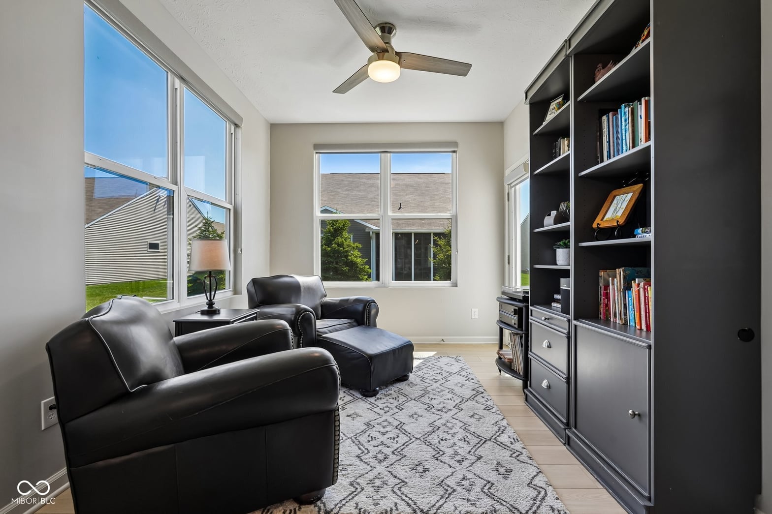 Bright family room with built-in shelving and leather seating.